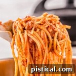 Effortless Instant Pot Spaghetti 8 scoop of instant pot spaghetti with the sauce mixed in held up over the instant pot.