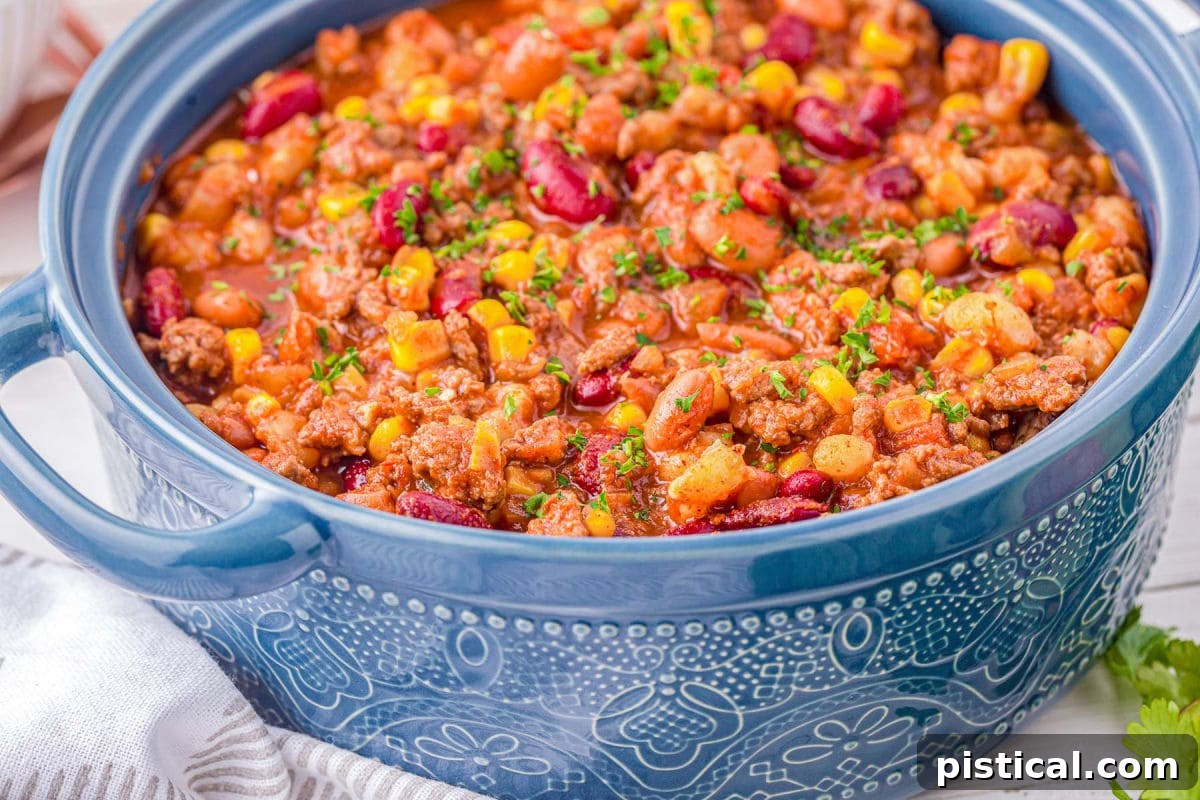 blue dutch oven filled to the brim with taco soup made with beef and beans.