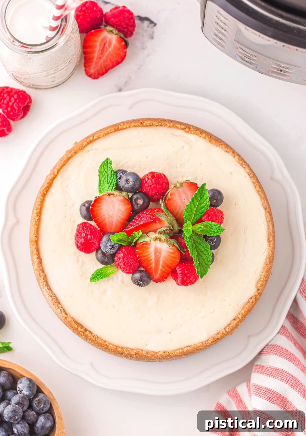 A stunning top-down view of a whole Instant Pot cheesecake, generously adorned with a vibrant medley of fresh berries, creating an appetizing and colorful display.