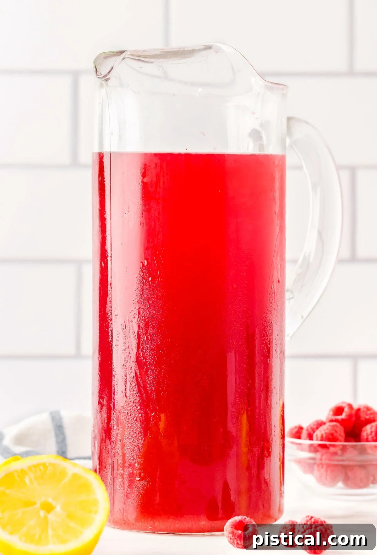 Ruby Red Raspberry Refresher 4 tall glass pitcher filled with raspberry iced tea ready to be enjoyed.