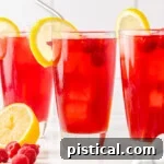 three tall glasses filled with raspberry iced tea and topped with a lemon slice.