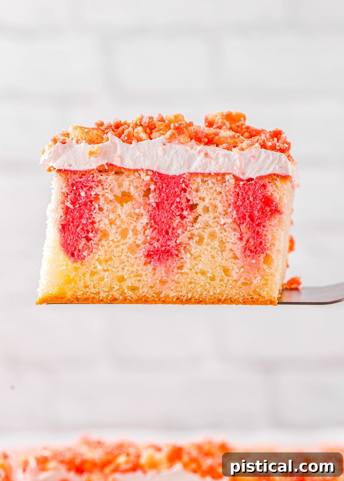 slice of strawberry poke cake recipe held up above the rest of the cake.