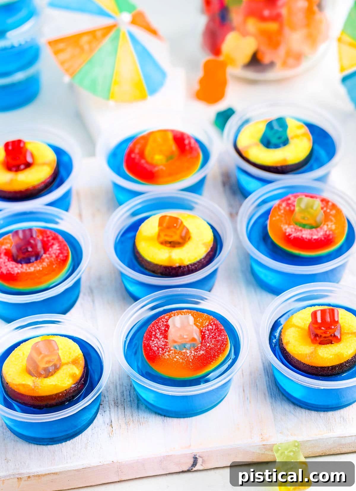 white tray topped with pool party jello shots. paper umbrellas and more gummy bears can be seen in the background.