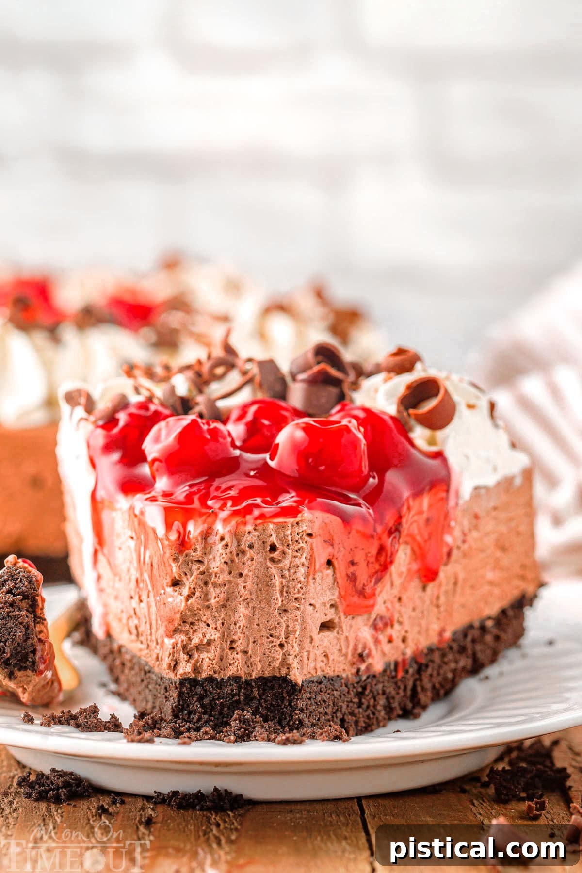 Piece of no bake black forest cheesecake recipe on plate with bite taken, showing the delicious layers and creamy texture.