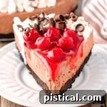 Slice of black forest cheesecake on white round plate.