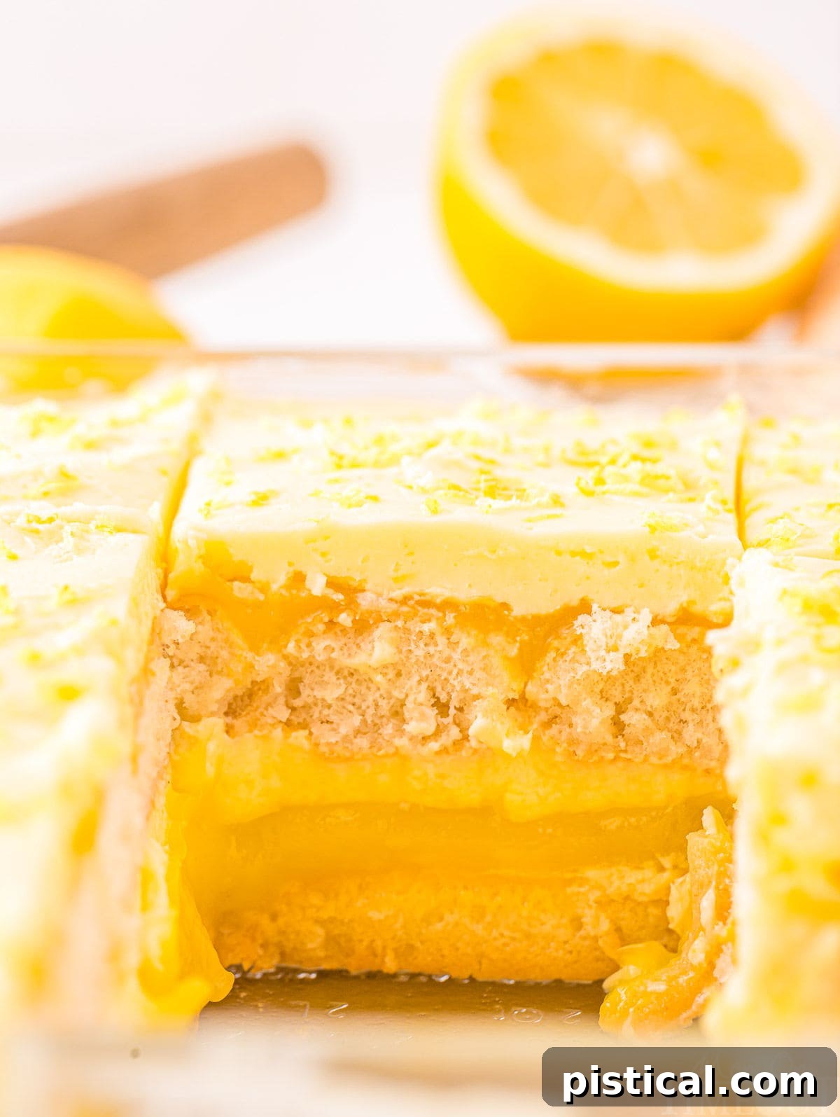 A serving of lemon tiramisu has been removed from a clear baking dish, revealing the perfectly formed, distinct layers of the refreshing dessert.