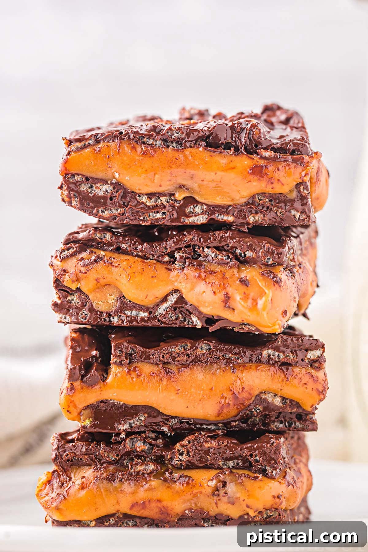 homemade 100 grand bar recipe cut into squares and stacked four high on a white plate.