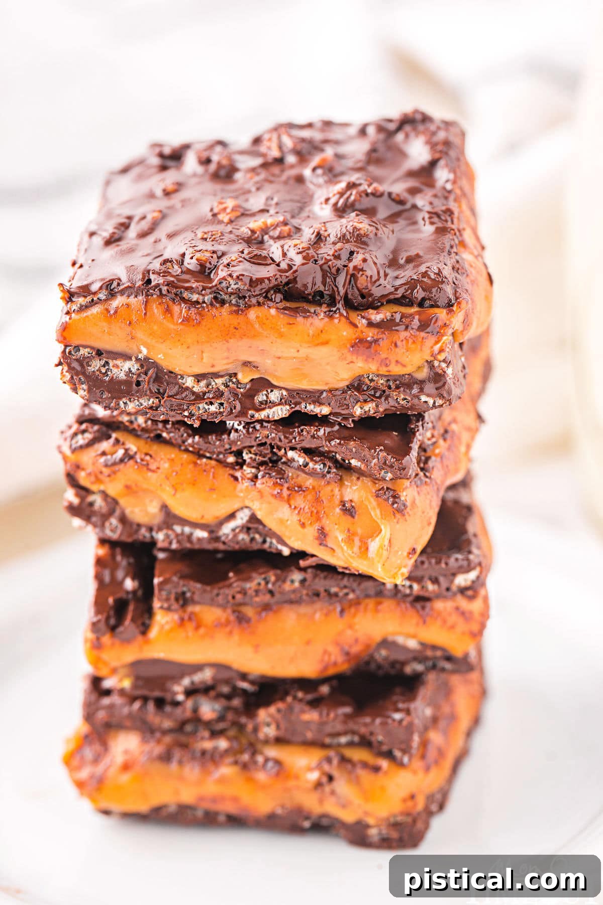 homemade 100 grand bar recipe cut into squares and stacked four high on a white plate.