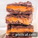 homemade 100 grand candy bars recipe cut into squares and stacked four high on a white plate.