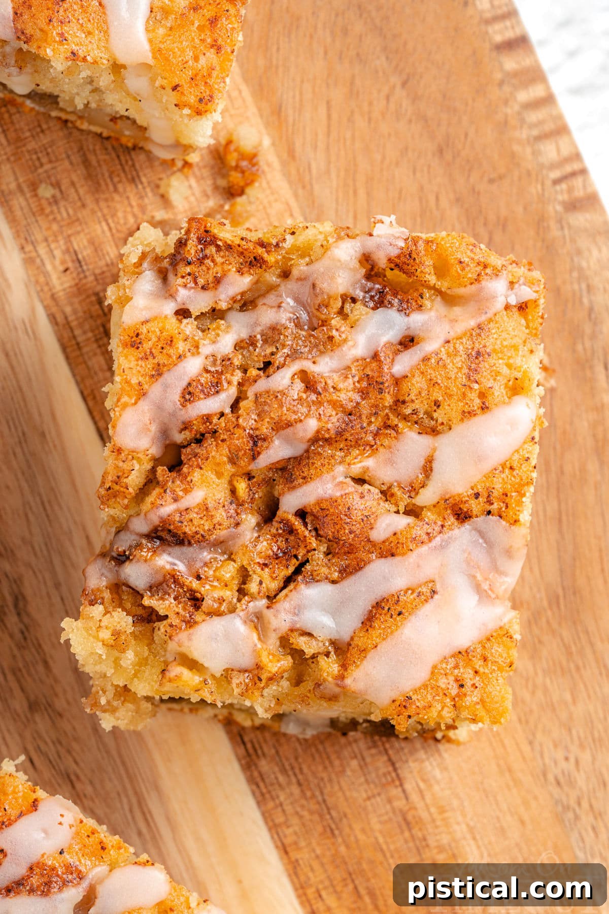 A top-down view of a single slice of apple cinnamon coffee cake with a delicate glaze, showcasing the golden crumb and apple chunks.