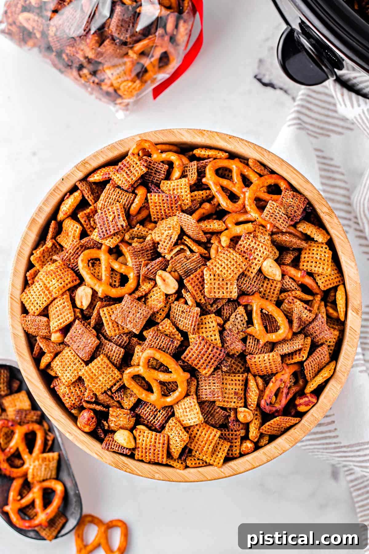 Top-down view of a large wooden bowl filled with crispy, golden crockpot Chex Mix, ready for serving.