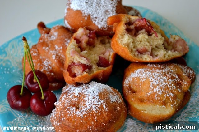 A close-up, tempting shot of a single cherry fritter, showing its fluffy texture and visible cherry pieces.