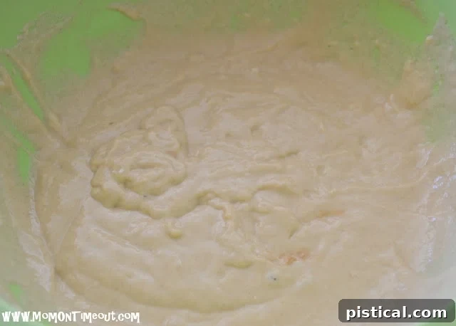 A bowl with liquid batter ingredients being mixed with a whisk, showing a smooth, creamy texture.