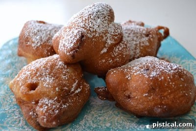 A close-up of a pile of cherry fritters, beautifully dusted with powdered sugar.