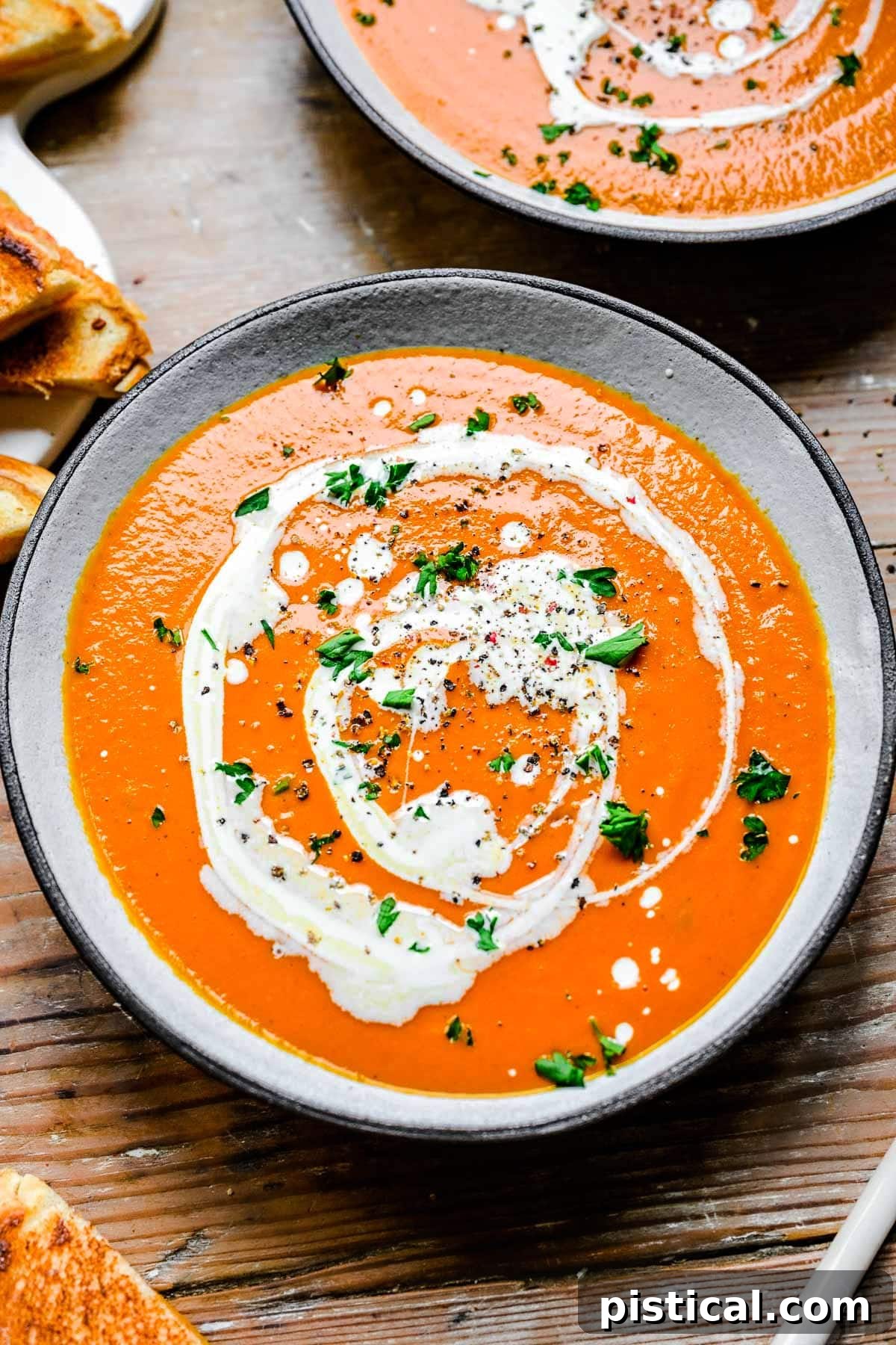 A comforting bowl of rich, red Instant Pot Tomato Soup, elegantly drizzled with heavy cream and garnished with fresh, chopped basil. It's a perfect cozy meal.