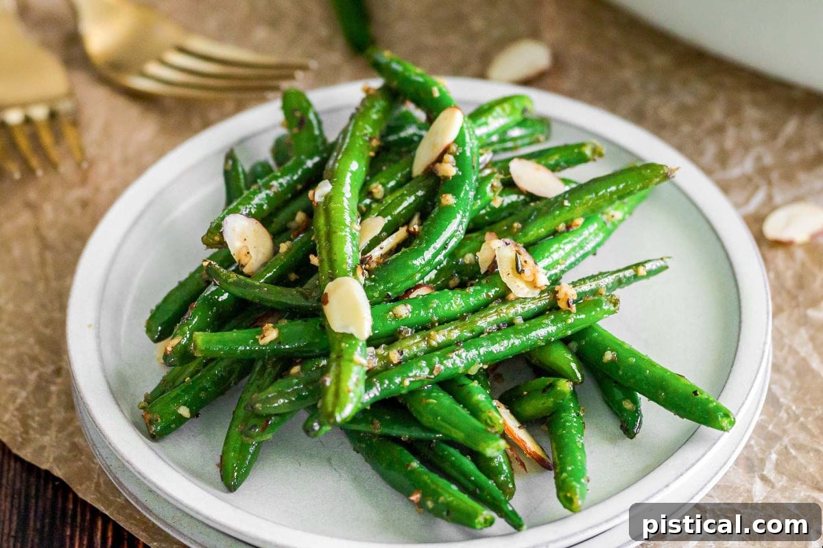 A small round white plate with a generous serving of brown butter garlic green beans, showing the vibrant green and glistening butter coating.