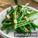 small round white plate with a serving of garlic green beans on it.