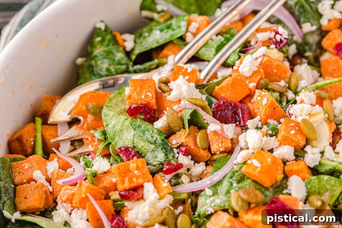 close up look at sweet potato salad in a large bowl with salad serving spoons.