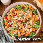 top down view of sweet potato salad in large serving bowl topped with dried cranberries and pepitas.