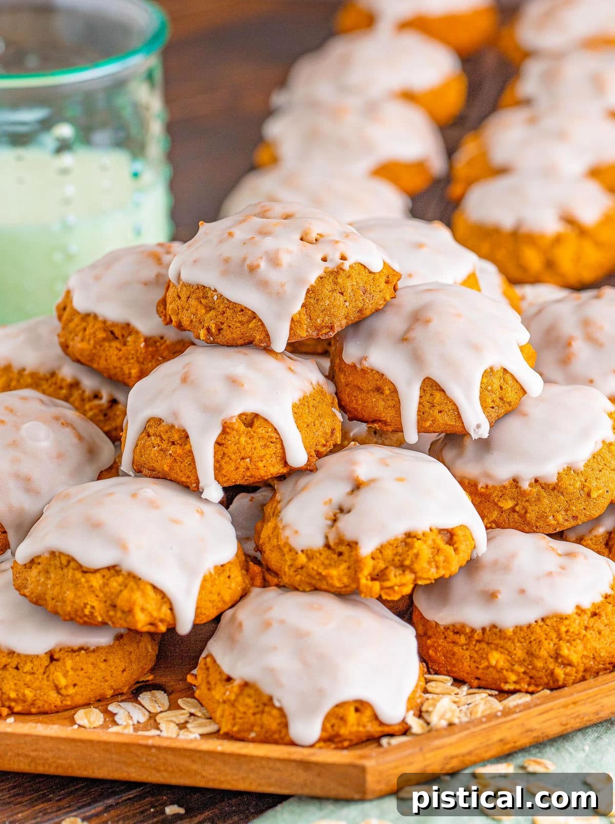 Wood board displaying a generous stack of perfectly iced pumpkin oatmeal cookies, ready for sharing.