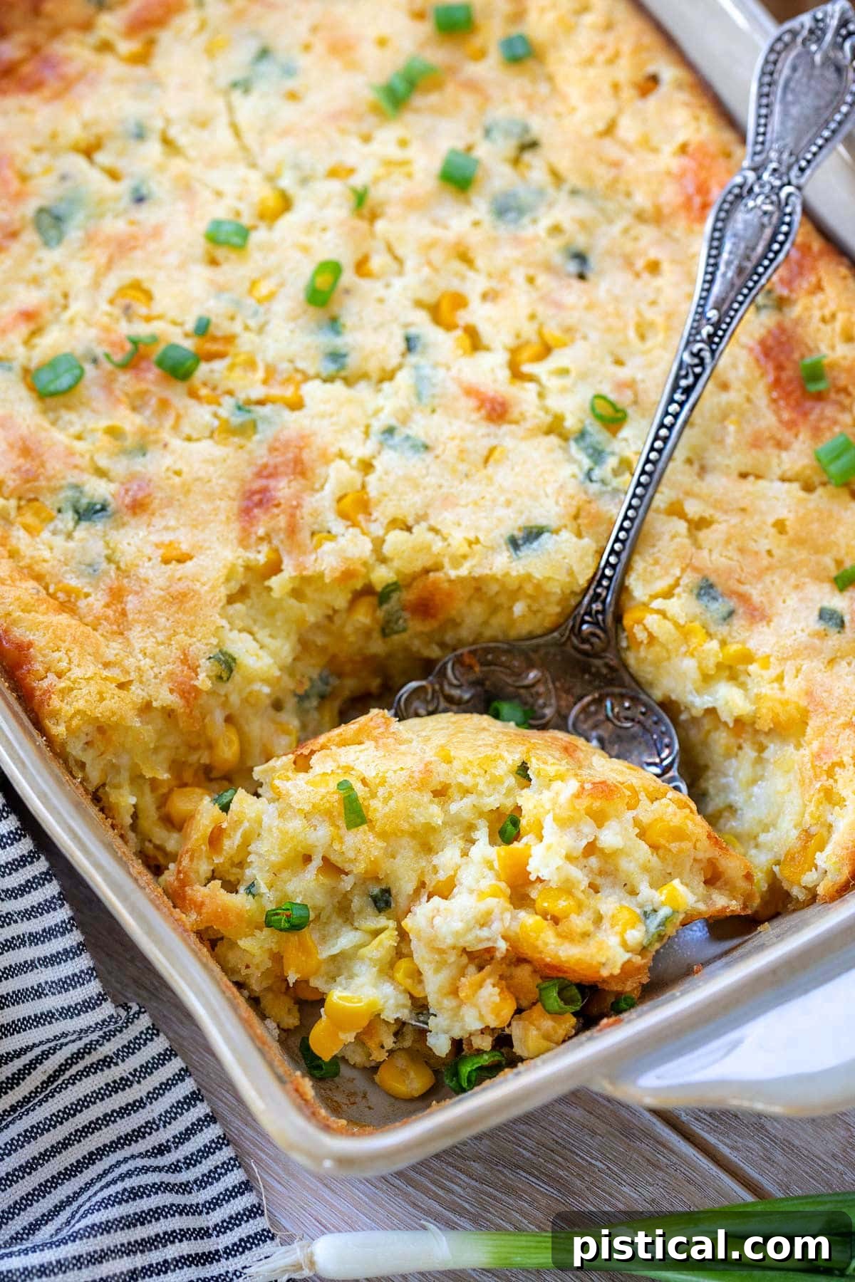 Scoop of creamy corn casserole being taken out of the baking dish, showing its rich, golden texture.