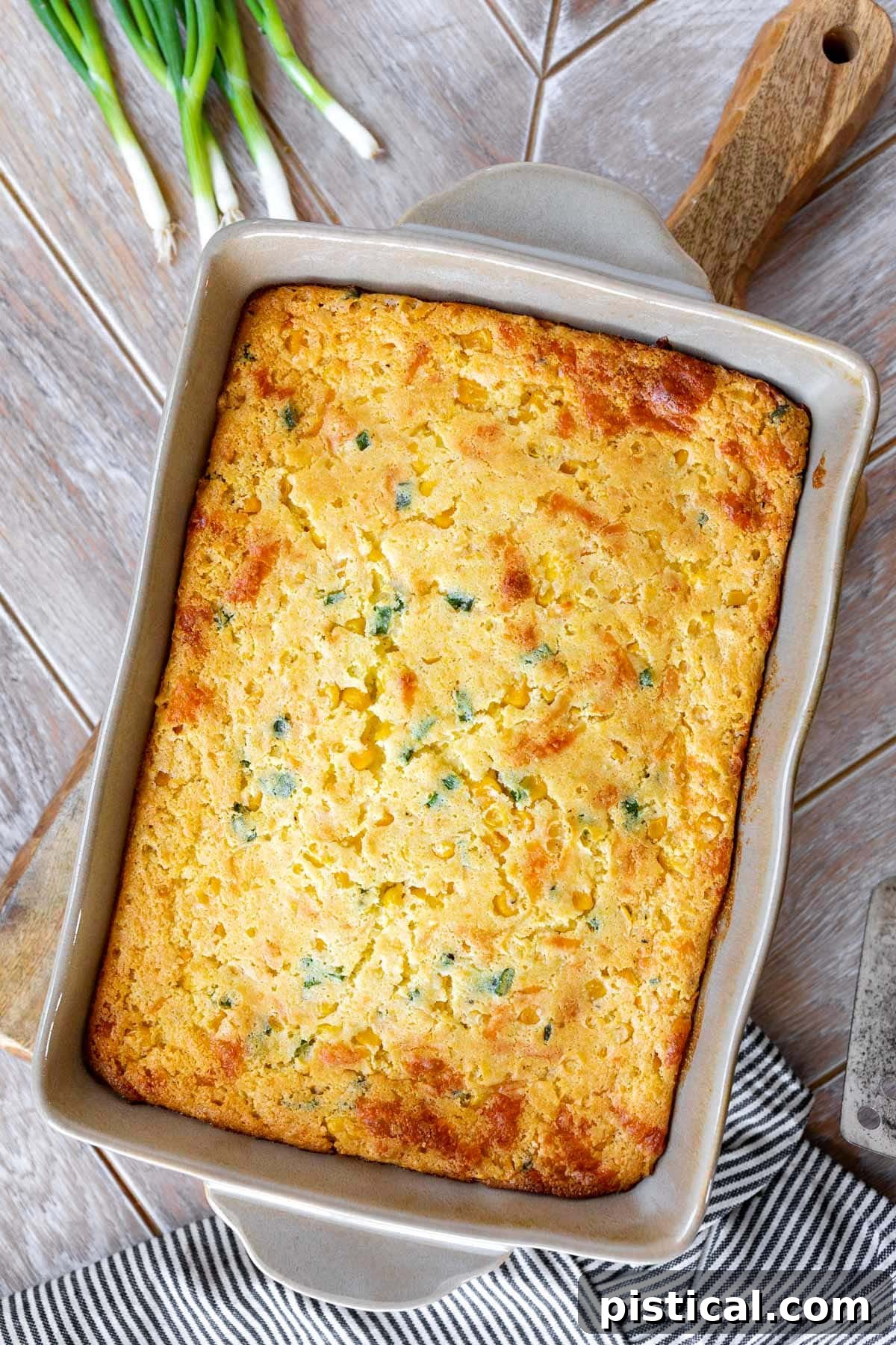 Top-down view of an untouched, perfectly baked jiffy corn casserole in a light tan casserole dish, showcasing its golden brown top.