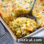 Scoop of creamy corn casserole being taken out of the baking dish.