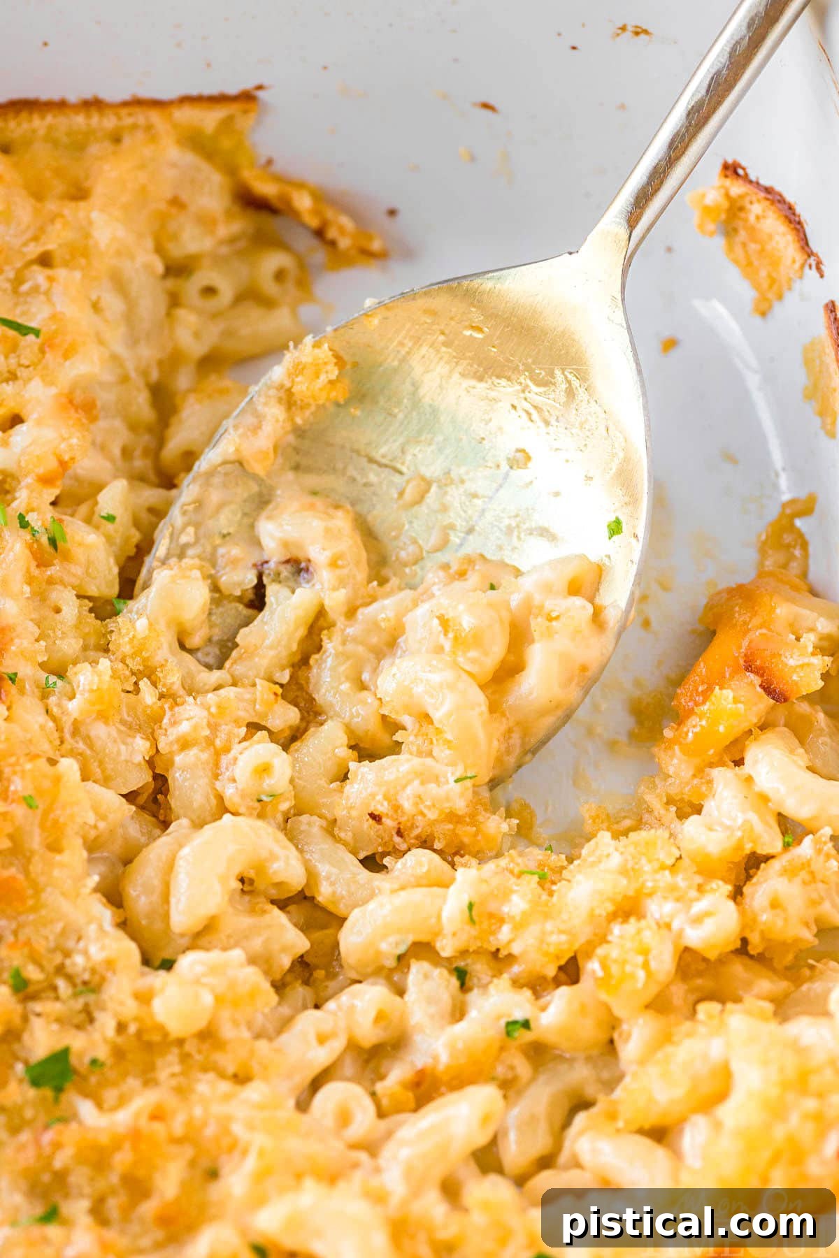 Top-down view of a casserole dish with a serving or two of baked Velveeta Mac and Cheese removed, showing its creamy texture.