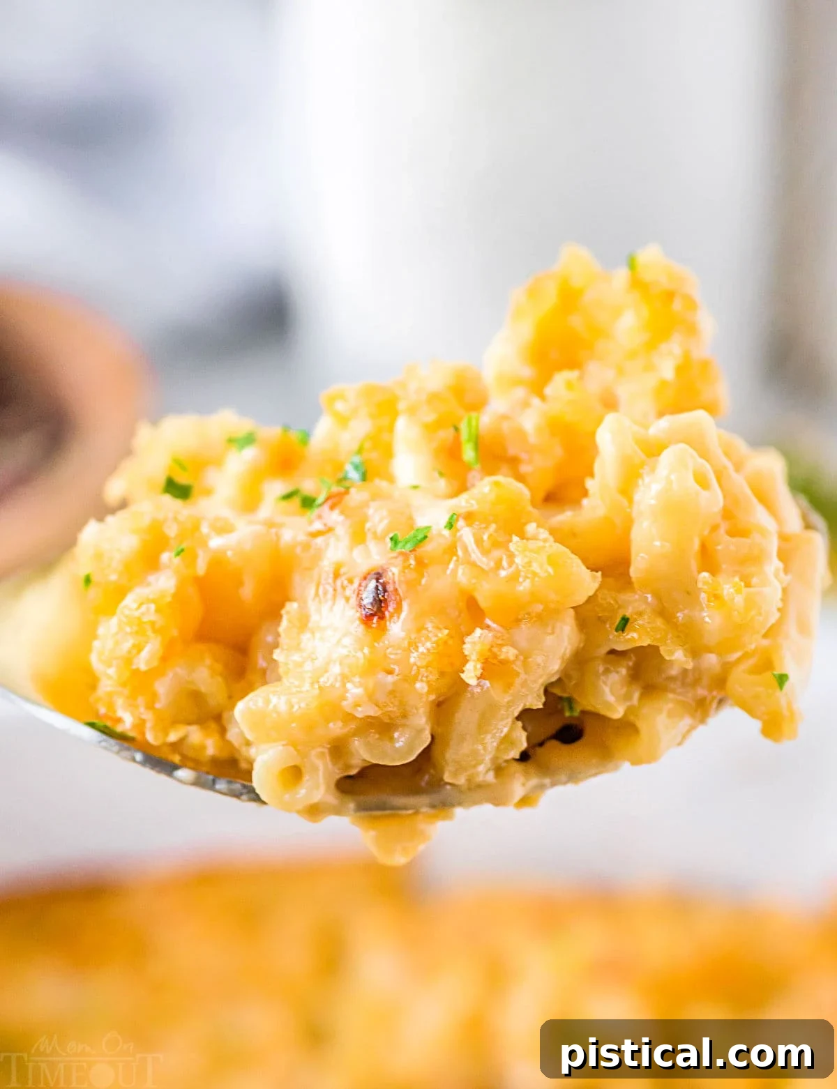 Large spoonful of creamy Velveeta Mac and Cheese held above the casserole dish, showcasing its rich texture.