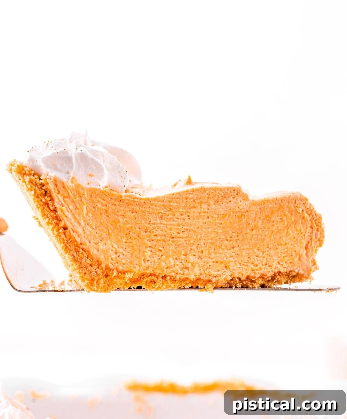 A tantalizing slice of no-bake pumpkin pie being lifted from the pie plate, showcasing its firm, yet creamy filling and golden-brown graham cracker crust. The image captures the anticipation of a delicious treat.