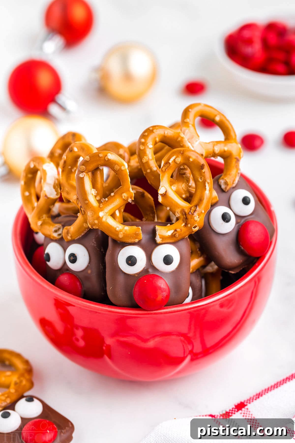 red bowl filled with reindeer pretzels with red candy noses and pretzel antlers.