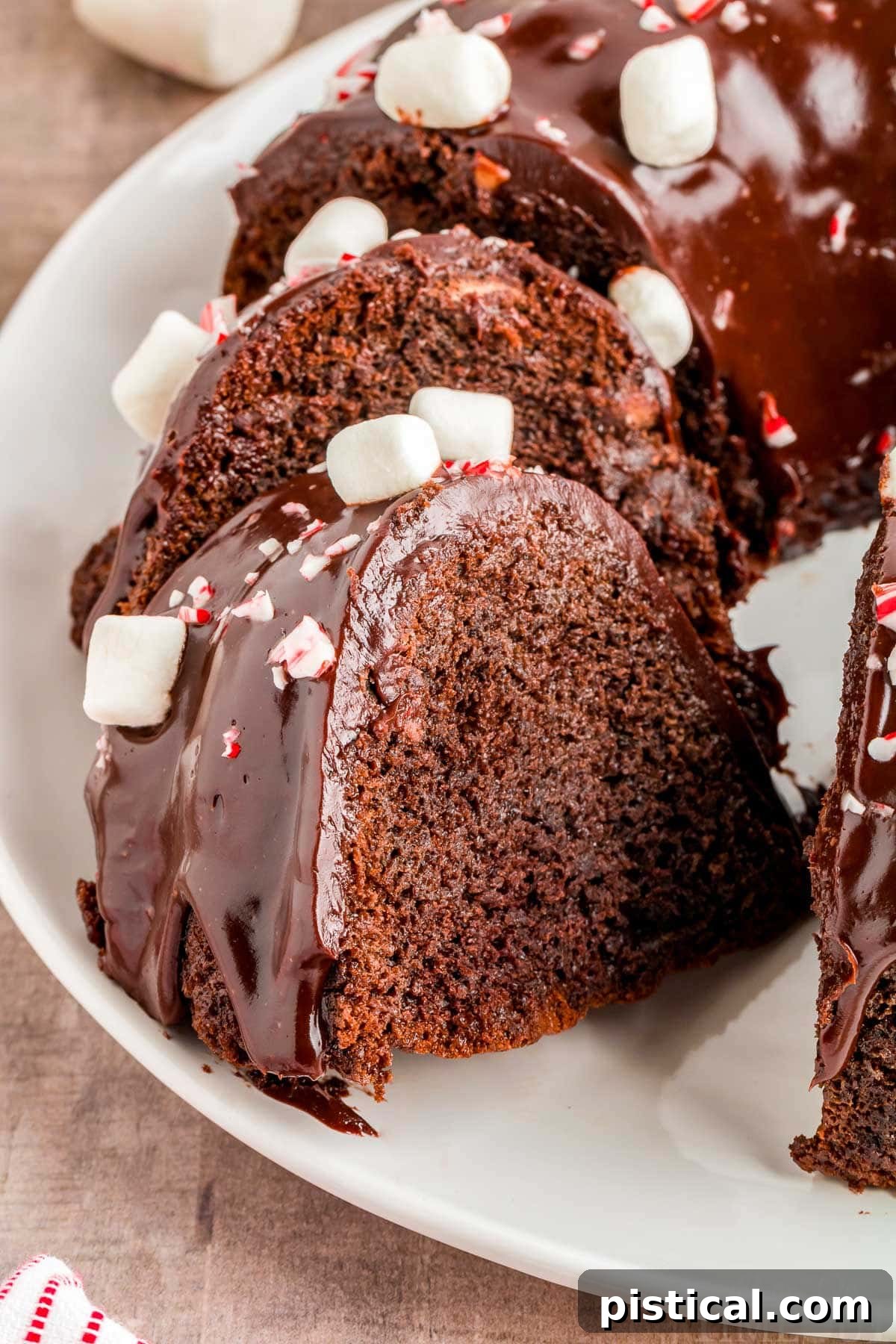 chocolate peppermint bundt cake on white plate with two slices cut out and sat an angle.