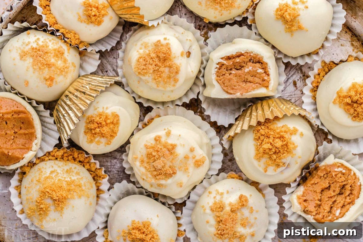 A top-down view showcasing a selection of easy gingerbread truffles, neatly arranged in white paper cups on a silver parchment tray. Three of the truffles have been perfectly bitten in half, revealing their soft, flavorful centers.