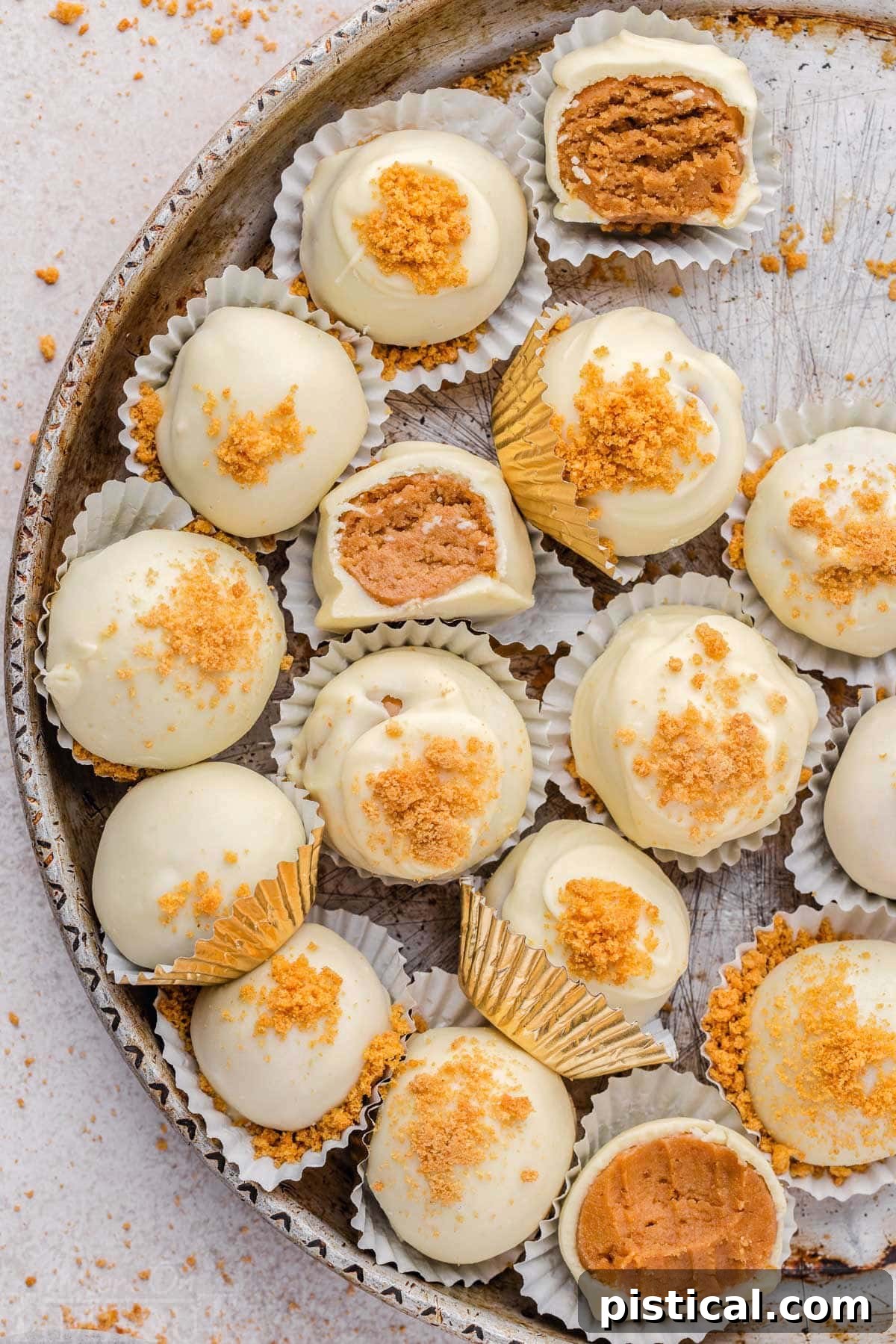 Gingerbread truffles artfully arranged in white paper cups, featuring gingersnap cookie crumble sprinkles atop a glossy white chocolate coating. Three of the truffles have been gracefully bitten, revealing their soft centers.