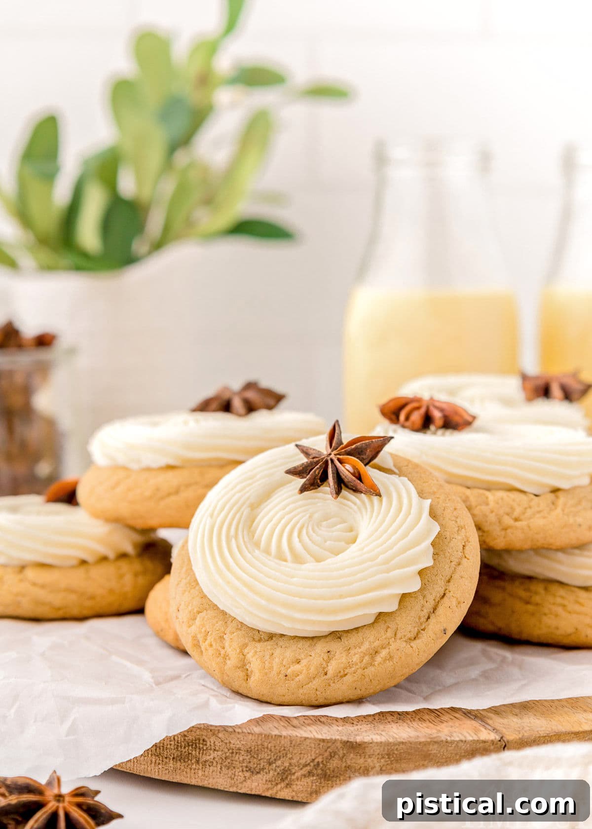 A close-up, pulled-back view of several beautifully frosted eggnog cookies resting on a wooden board. Each cookie features a thick, artfully piped swirl of creamy eggnog frosting, highlighting their inviting texture and festive appeal.