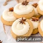 A charming stack of freshly baked eggnog cookies on a rustic wooden cutting board. Each cookie is generously topped with a thick swirl of creamy eggnog frosting and delicately garnished with a star anise, creating a beautiful and aromatic presentation.