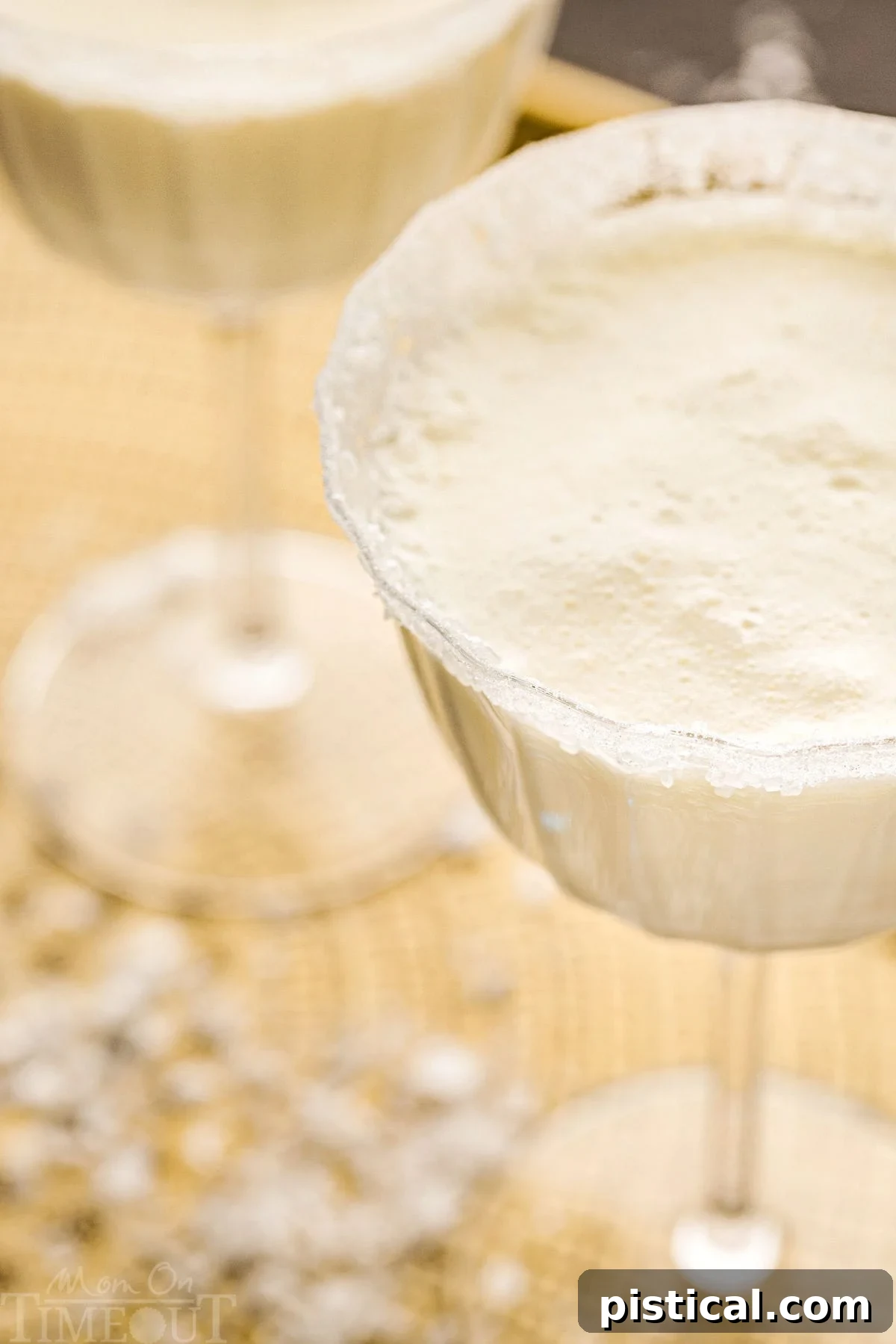 angled top down view of white martini in tall glass dusted with sugar for a snowy look.