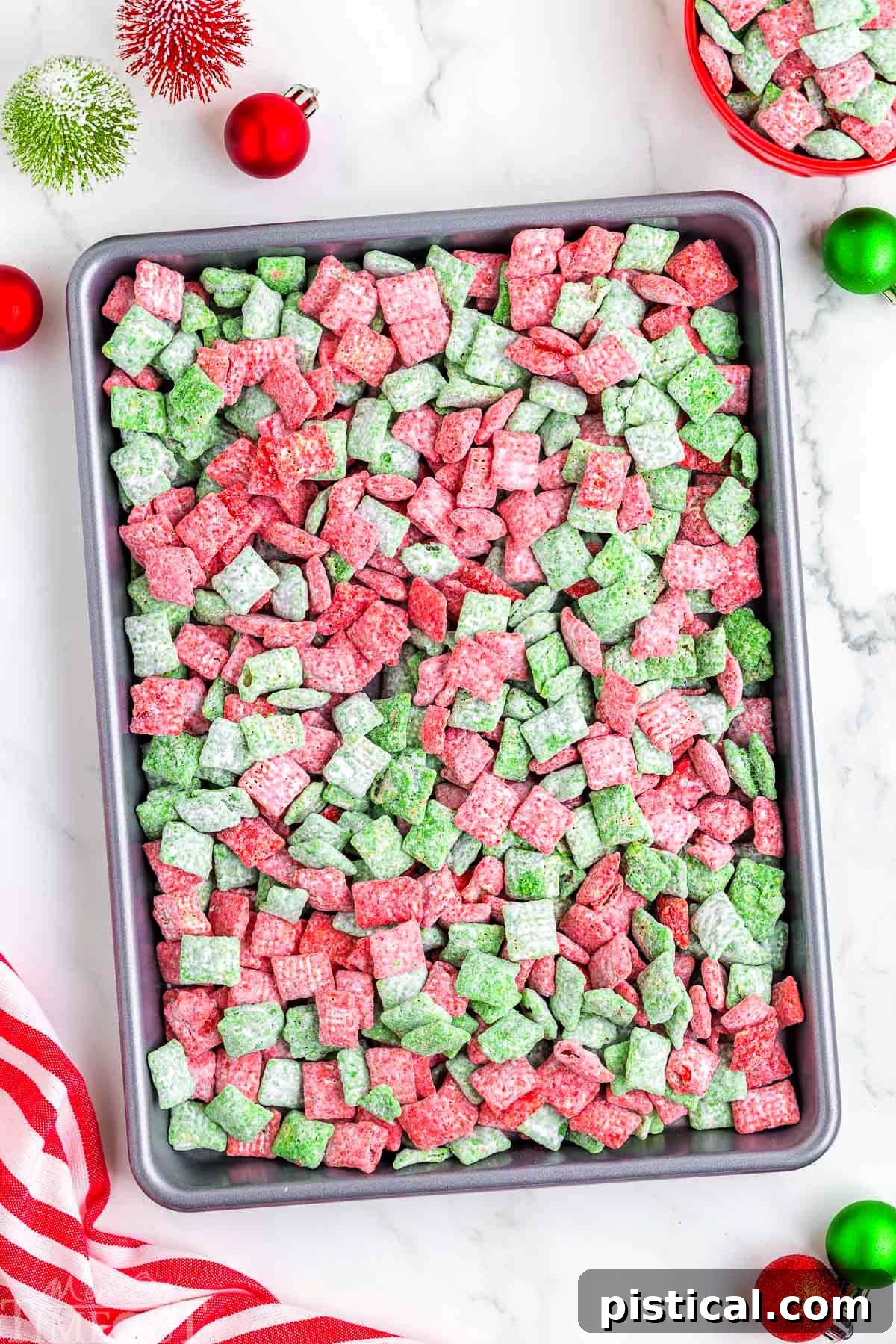 top down look at christmas muddy buddies recipe spread out on a sheet pan.