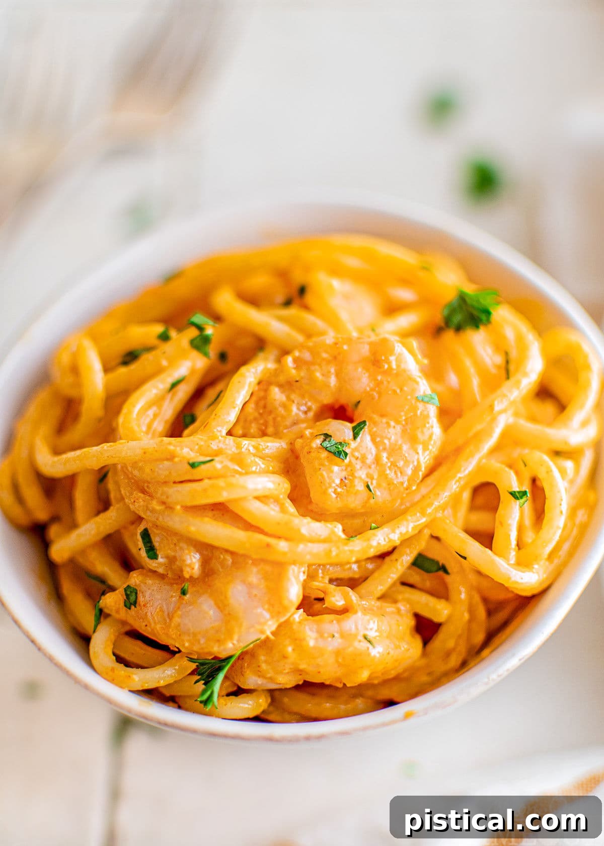 Small white bowl filled with Bang Bang Shrimp Pasta, garnished with fresh parsley.