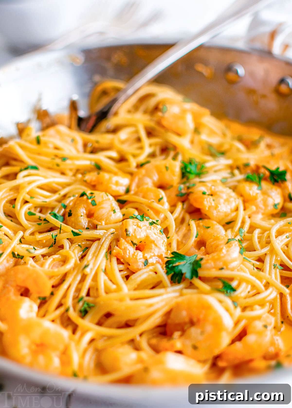 Close-up of Bang Bang Shrimp Pasta in a large stainless steel skillet, topped with fresh parsley.