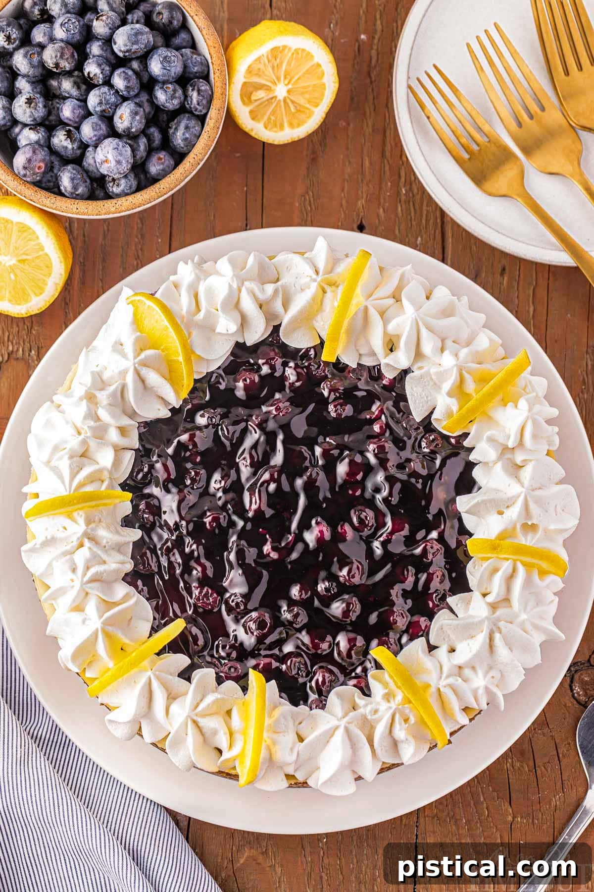 Luscious Lemon Blueberry Cheesecake 5 top down look at the blueberry pie filling on top of a lemon cheesecake. small bowl of blueberries next to the cheesecake.