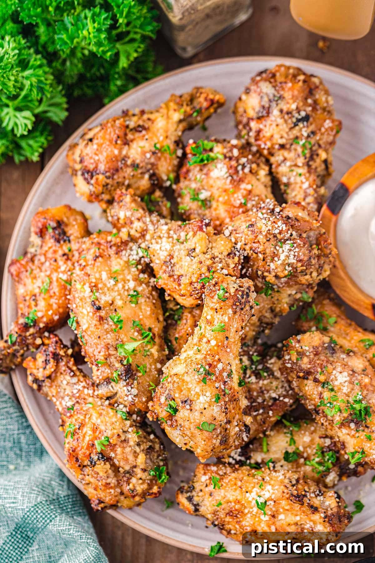top down look at plate filled with garlic parmesan chicken wings that have been coated with Parmesan and garnished with freshly chopped parsley. 