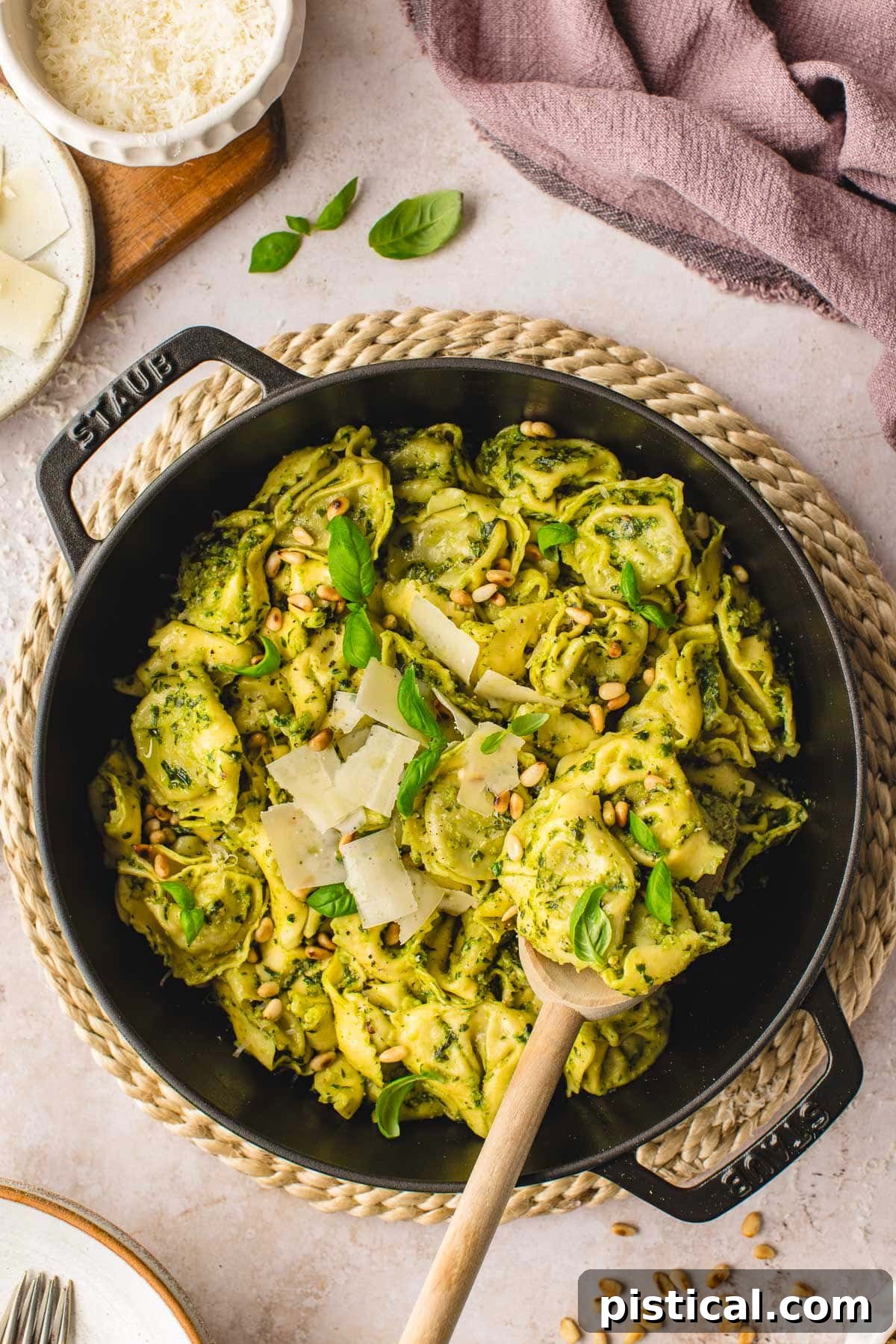 Top-down view of Pesto Tortellini in a black cast iron skillet, garnished with fresh basil and Parmesan cheese.