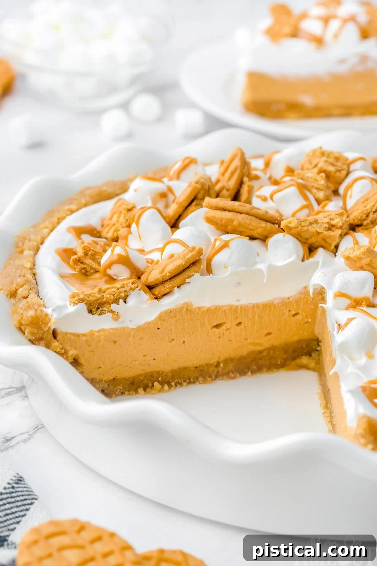Fluffernutter Pie in white pie dish with one slice removed, revealing the creamy layers and crispy crust, ready to be enjoyed.