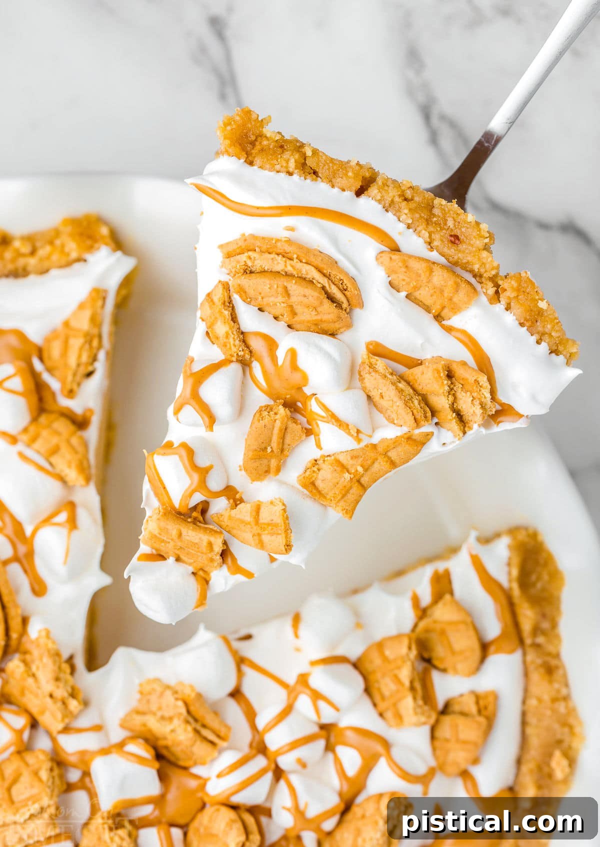 Piece of fluffernutter pie being lifted out of the white pie dish, showing the perfect layers of crust, peanut butter filling, and marshmallow topping.