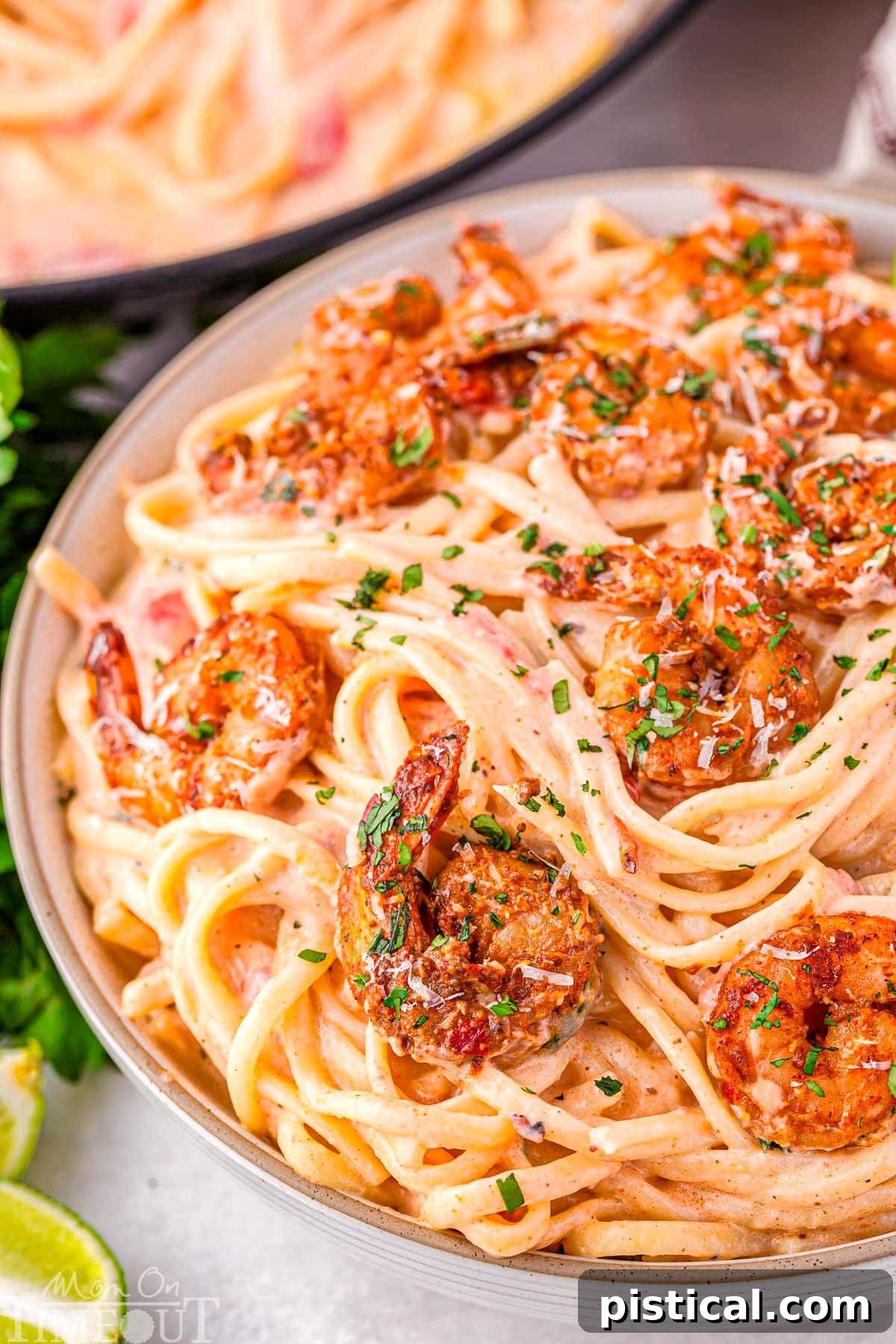 Close up look at bowl of creamy Cajun shrimp pasta with a rich Parmesan cream sauce and topped with spicy shrimp and garnished with fresh parsley.