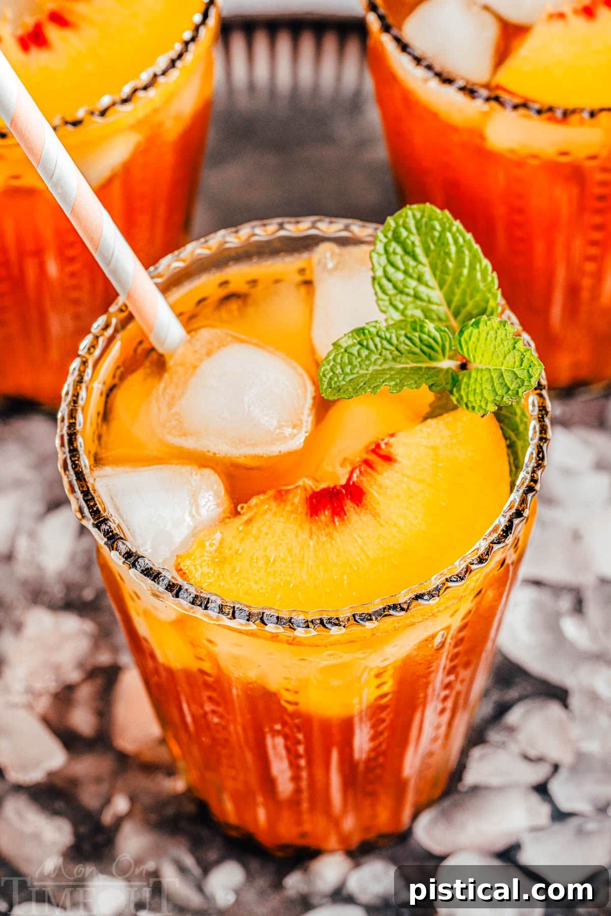Sun-Kissed Peach Sip 8 Three tall glasses filled with homemade peach iced tea, topped with fresh peach slices and a sprig of mint. The glasses are displayed on a tray covered with ice for cooling.