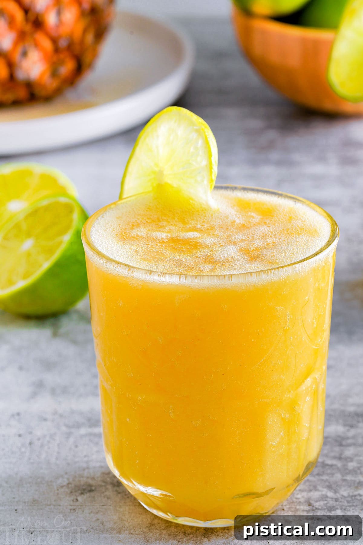 A close-up side view of a beautifully prepared pineapple mango mocktail, garnished with a vibrant lime wedge, ready to be enjoyed.