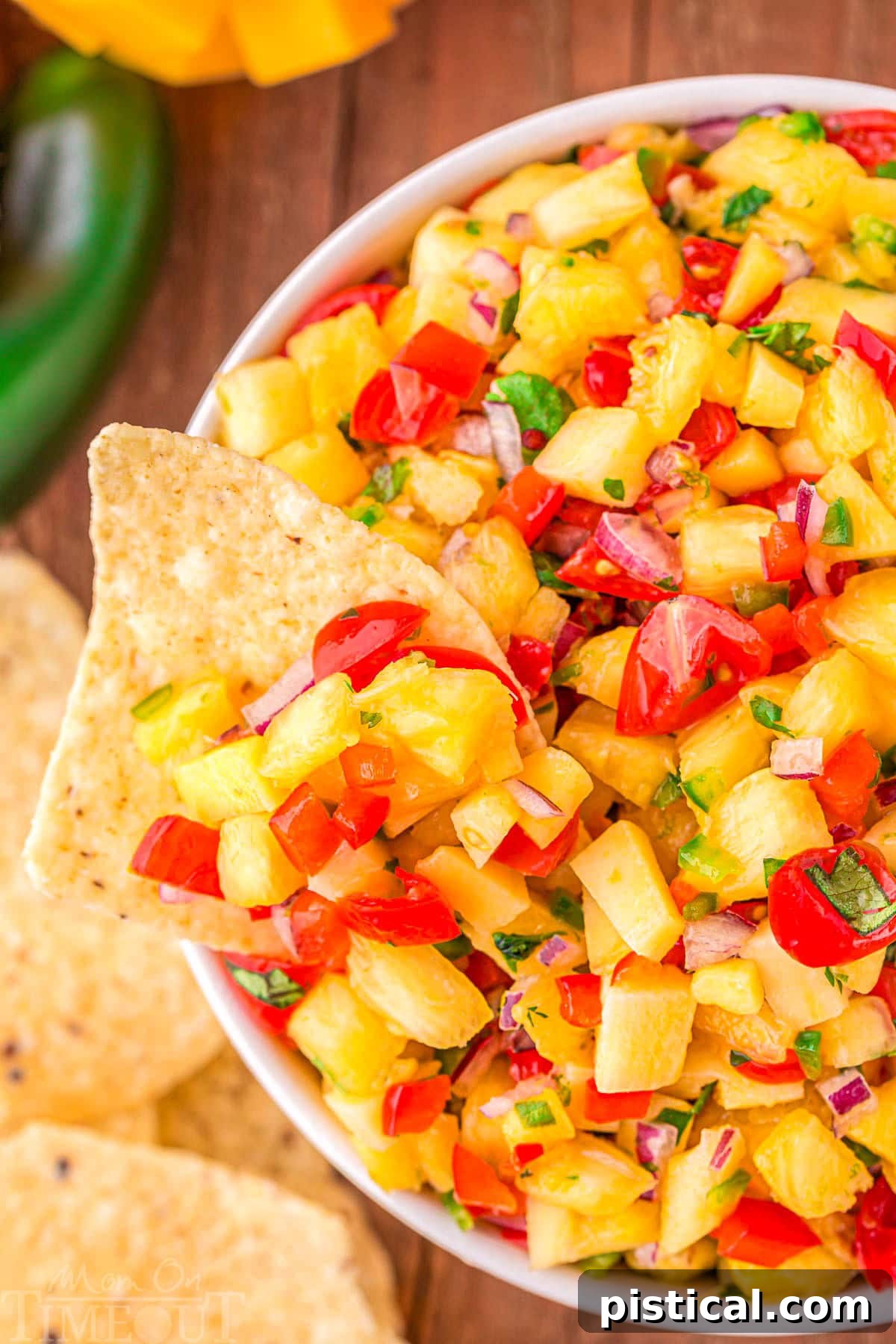 bowl of pineapple mango salsa with a chip dipped into the bowl.