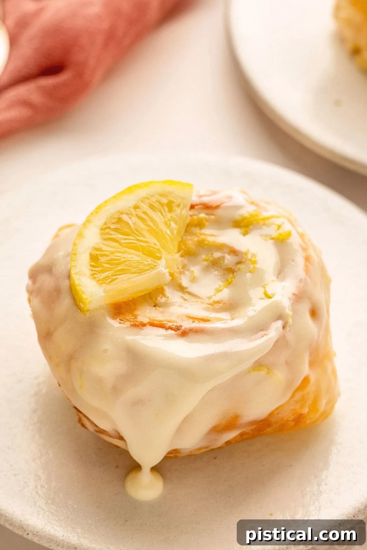 Zesty Lemon Swirls 4 A single lemon roll on a pristine white plate, showcasing its soft texture and glistening glaze.